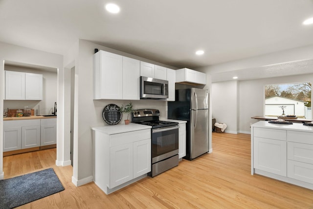 kitchen featuring stainless steel appliances, recessed lighting, light countertops, light wood-style floors, and white cabinetry