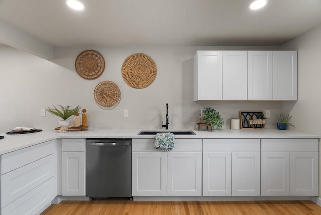 kitchen with a sink, light wood-style floors, light countertops, and stainless steel dishwasher