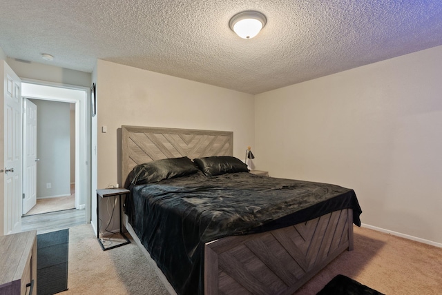 bedroom featuring light carpet, baseboards, and a textured ceiling