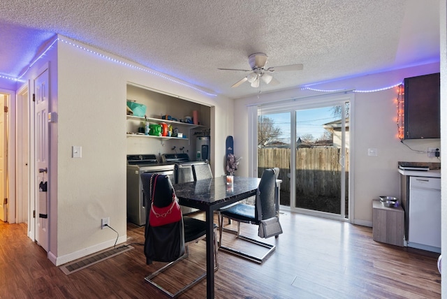 dining room featuring a textured ceiling, wood finished floors, a ceiling fan, baseboards, and washer and clothes dryer