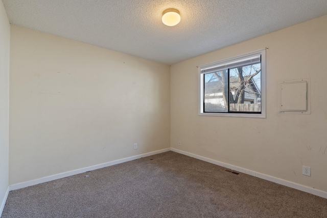 unfurnished room with visible vents, a textured ceiling, baseboards, and carpet flooring