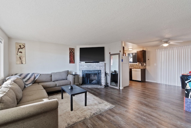 living room featuring dark wood-style floors, a fireplace, a ceiling fan, and a textured ceiling