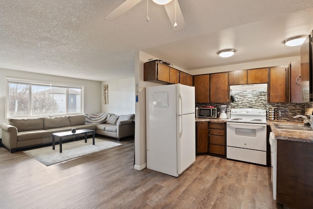 kitchen featuring white appliances, tasteful backsplash, light wood-style flooring, open floor plan, and a sink