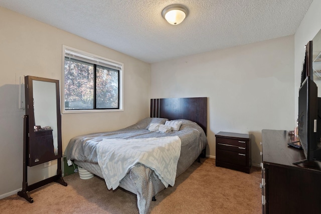 bedroom featuring light carpet, baseboards, and a textured ceiling