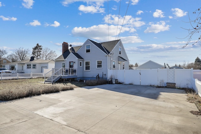 view of front of home featuring fence private yard, a gate, and a chimney