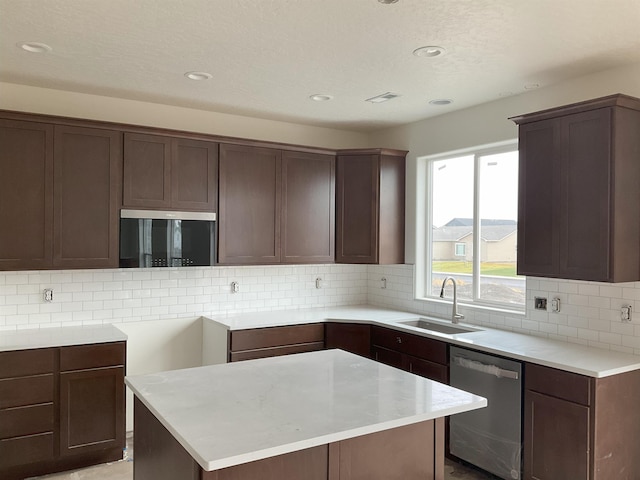 kitchen featuring a sink, a center island, dark brown cabinets, stainless steel dishwasher, and decorative backsplash