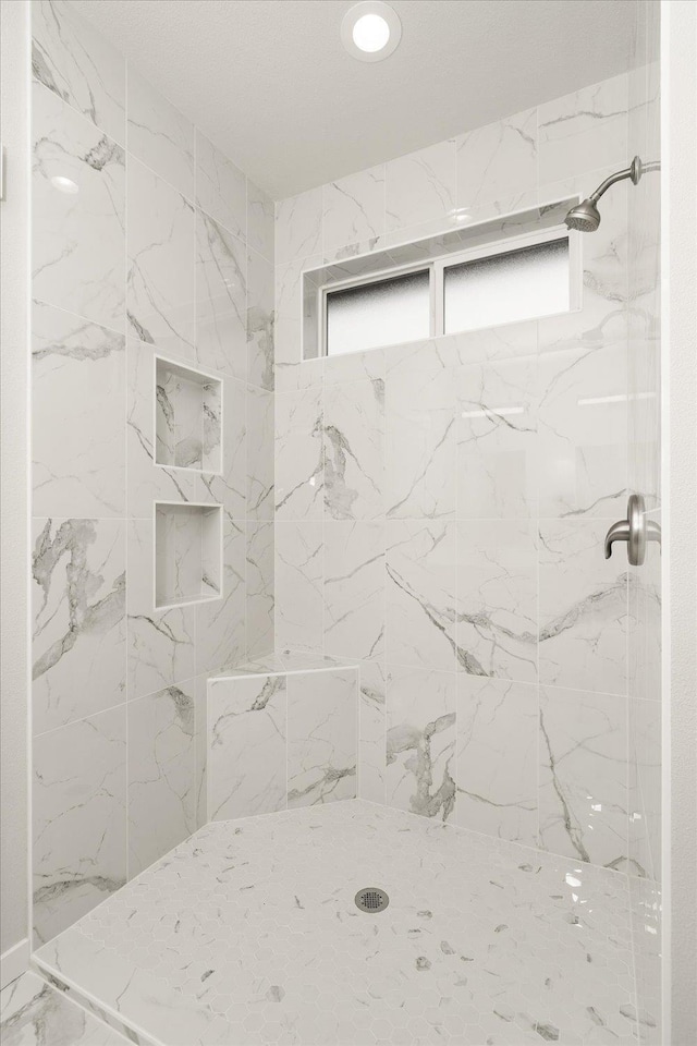 bathroom featuring marble finish floor and tiled shower