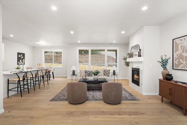 interior space featuring light wood-type flooring, recessed lighting, baseboards, and a glass covered fireplace