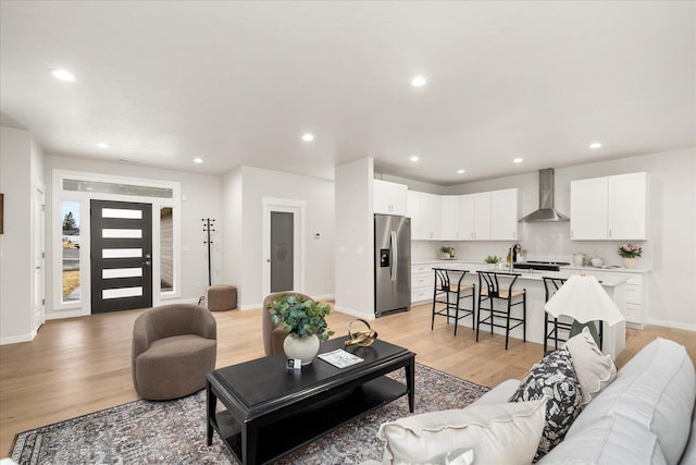 living room with light wood-type flooring, baseboards, and recessed lighting