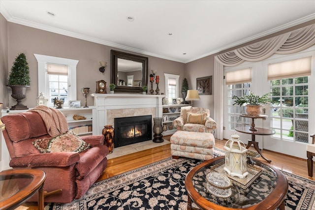 living room with a fireplace with flush hearth, wood finished floors, a wealth of natural light, and crown molding