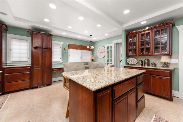 kitchen with recessed lighting, light stone countertops, tasteful backsplash, glass insert cabinets, and pendant lighting