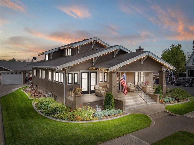 view of front of property featuring an outdoor structure, french doors, a lawn, stucco siding, and a chimney