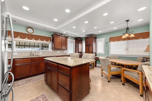 kitchen with freestanding refrigerator, hanging light fixtures, a sink, backsplash, and recessed lighting