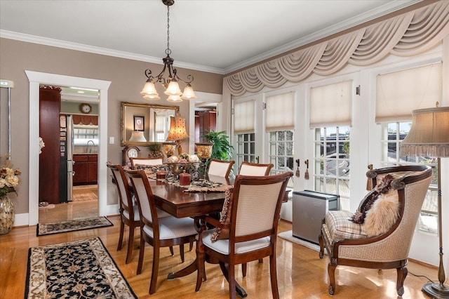 dining room featuring light wood-type flooring, baseboards, a chandelier, and crown molding