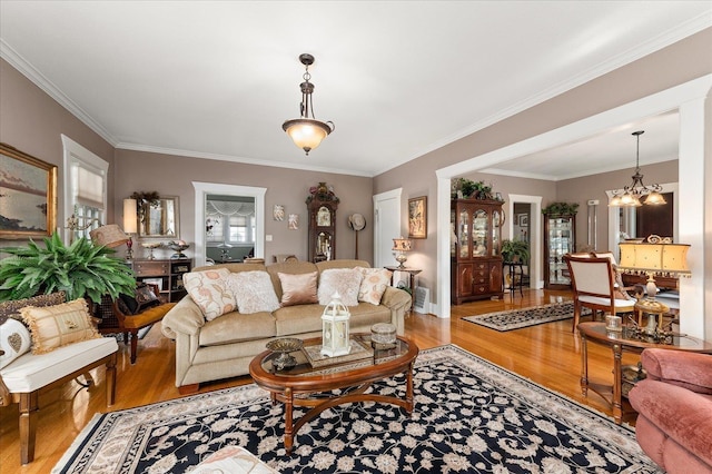 living area featuring a chandelier, light wood finished floors, and crown molding