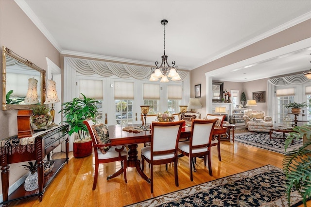 dining area with light wood-type flooring, a chandelier, and ornamental molding