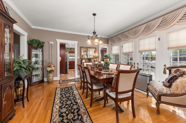 dining area featuring light wood-type flooring, an inviting chandelier, baseboards, and crown molding