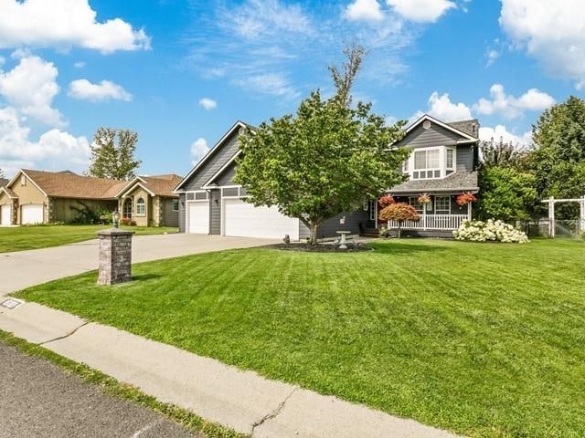 view of front facade with a garage, driveway, a front yard, and fence