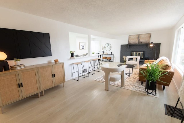 living room featuring light wood-style floors, a fireplace, visible vents, and a textured ceiling