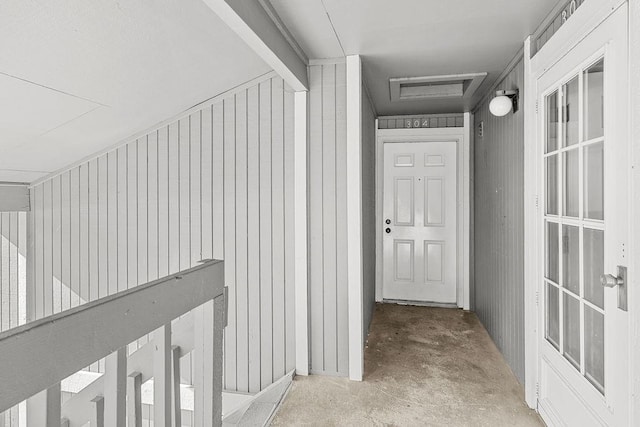 hall with attic access and unfinished concrete flooring