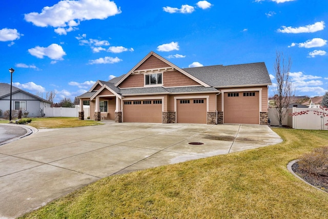 craftsman house with roof with shingles, concrete driveway, fence, stone siding, and a front lawn