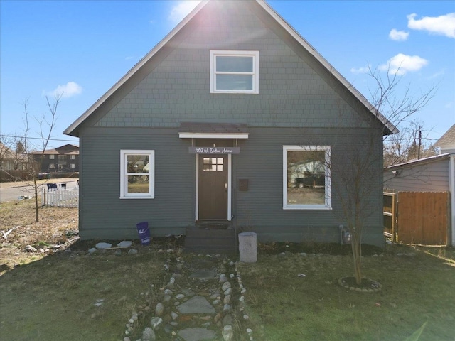 bungalow-style house featuring entry steps, fence, and a front lawn