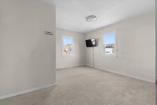 carpeted empty room with visible vents, baseboards, and a textured ceiling