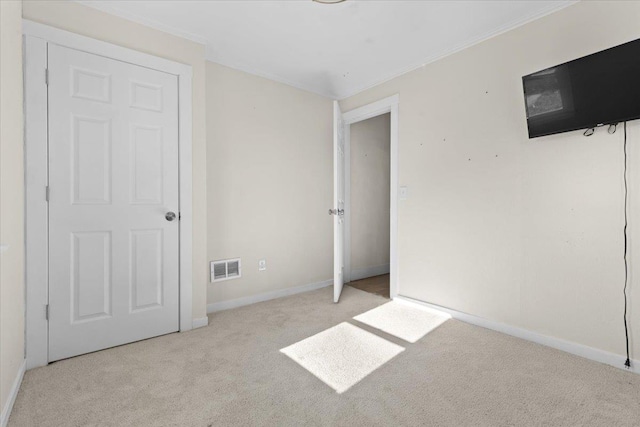 unfurnished bedroom featuring baseboards, visible vents, carpet flooring, and ornamental molding