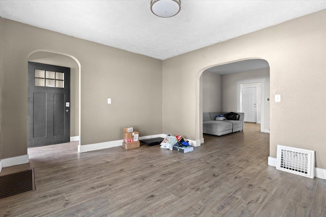 foyer featuring visible vents, arched walkways, and wood finished floors