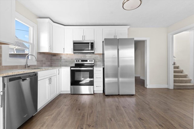 kitchen featuring appliances with stainless steel finishes, light stone countertops, white cabinets, and tasteful backsplash