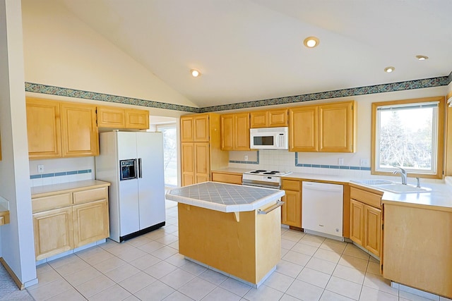 kitchen featuring light brown cabinetry, white appliances, a sink, and tile counters