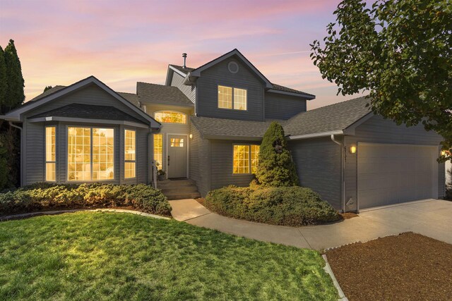 traditional home with a garage, concrete driveway, roof with shingles, and a front yard