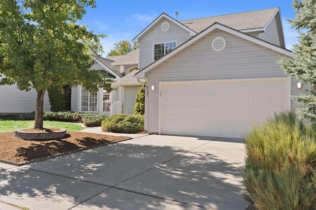 traditional-style home featuring concrete driveway, an attached garage, and roof with shingles