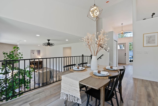 dining room featuring light wood finished floors, recessed lighting, baseboards, and a towering ceiling