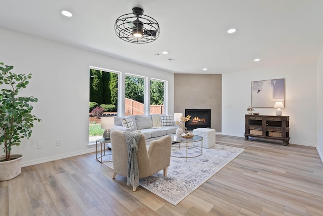 living room featuring recessed lighting, baseboards, light wood finished floors, and a large fireplace