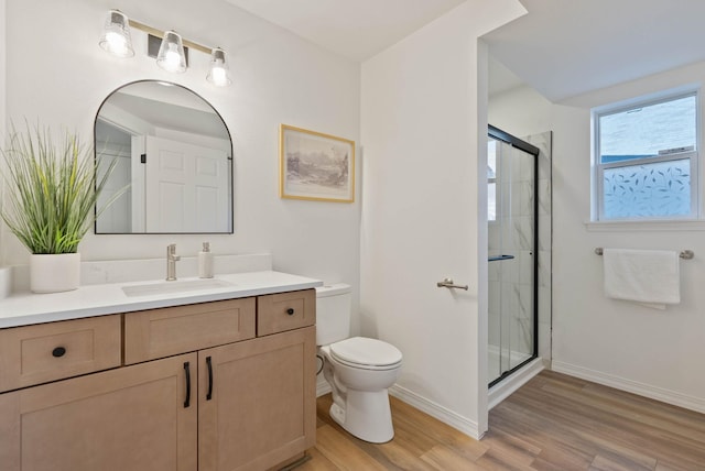 bathroom featuring baseboards, wood finished floors, toilet, and a stall shower