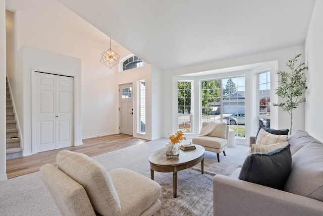 living room featuring high vaulted ceiling, light wood-type flooring, plenty of natural light, and stairway