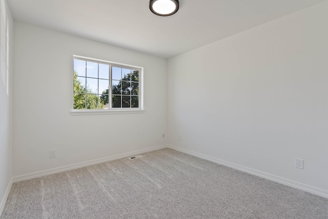 carpeted spare room featuring visible vents and baseboards