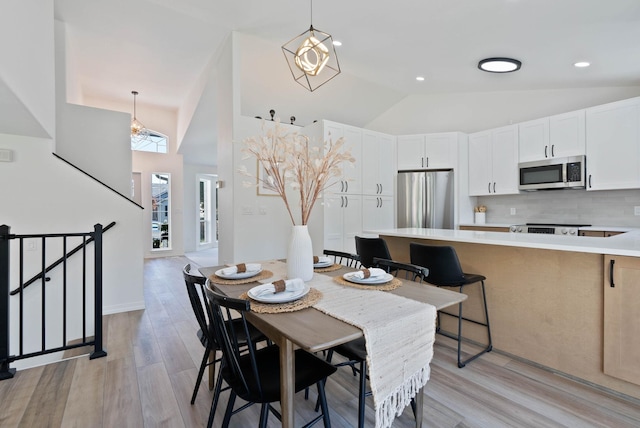 dining area with baseboards, recessed lighting, high vaulted ceiling, and light wood-style floors