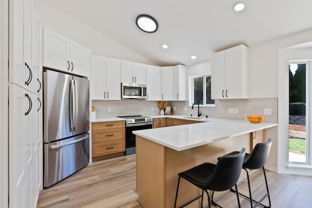 kitchen featuring backsplash, a breakfast bar, a peninsula, stainless steel appliances, and a sink