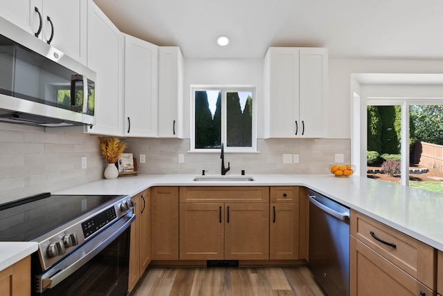 kitchen featuring a sink, stainless steel appliances, light countertops, light wood-style floors, and tasteful backsplash