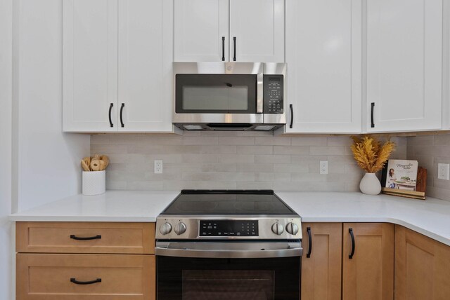 kitchen with light countertops, white cabinets, tasteful backsplash, and appliances with stainless steel finishes