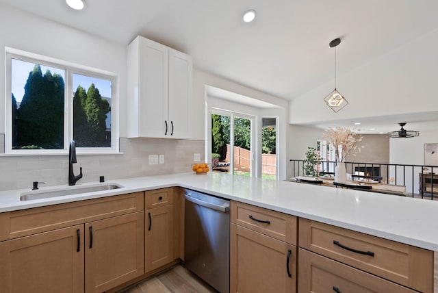 kitchen featuring tasteful backsplash, light countertops, a peninsula, stainless steel dishwasher, and a sink