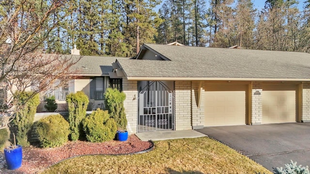 view of front facade with aphalt driveway, brick siding, a shingled roof, and a garage