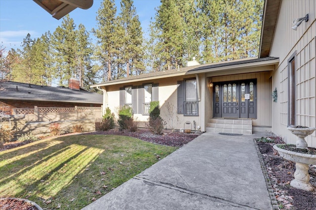 property entrance with stucco siding, a yard, and fence