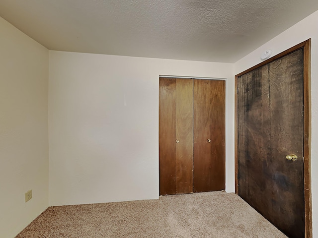 unfurnished bedroom with two closets, a textured ceiling, and carpet flooring