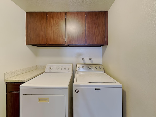 washroom with cabinet space, separate washer and dryer, and a textured ceiling