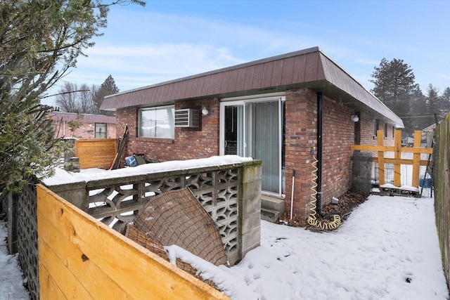 exterior space featuring a wall mounted air conditioner, fence, and brick siding