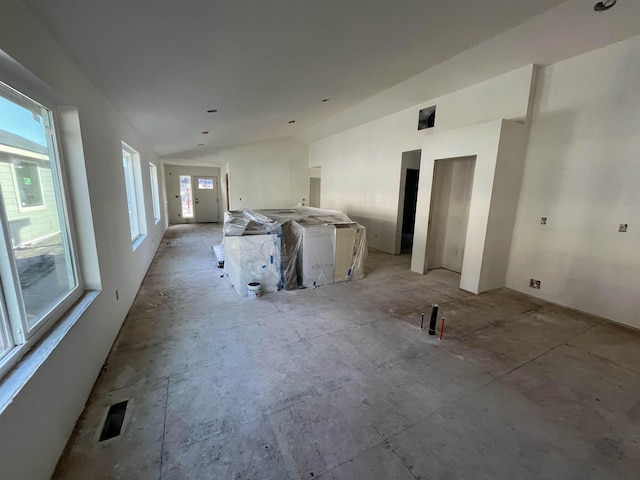 empty room featuring lofted ceiling, visible vents, and a wealth of natural light