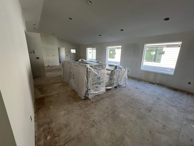 interior space with vaulted ceiling, a large island, open floor plan, and white cabinetry